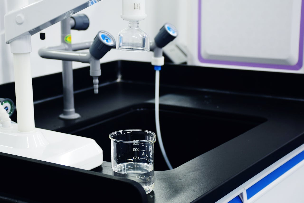 Close-up of laboratory equipment used for water filtration, featuring beakers and faucets.
